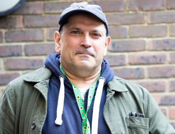 A middle aged man wearing a hoodie and cap