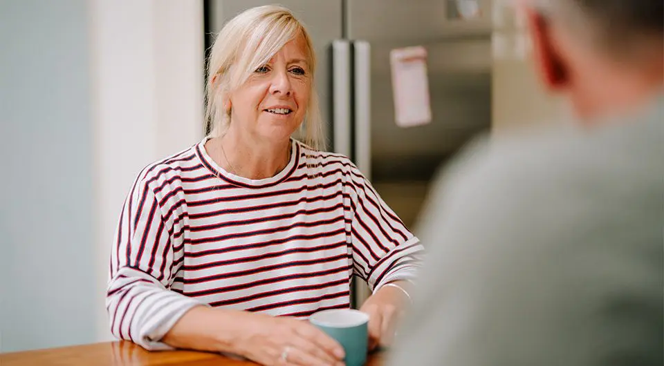 A woman shares a cup of tea with a supportive friend at home